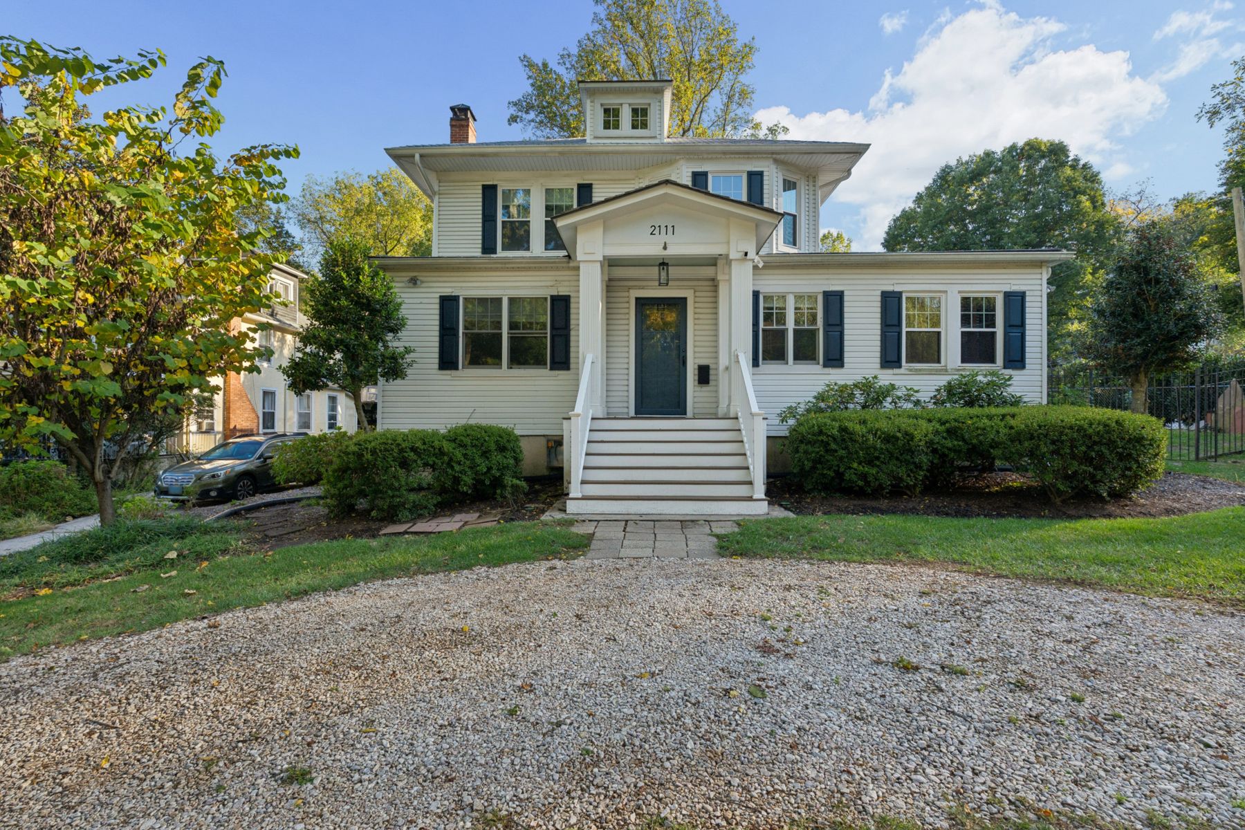 Front of 2111 Carterdale Road: a white foursquare with navy shutters, a columned entry portico and a circular gravel drive
