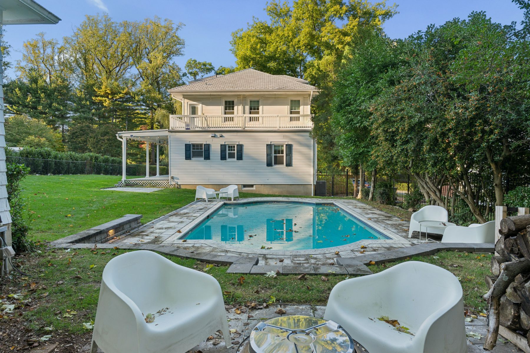 Back of the house seen across the pool, with the second-floor balcony and covered porch