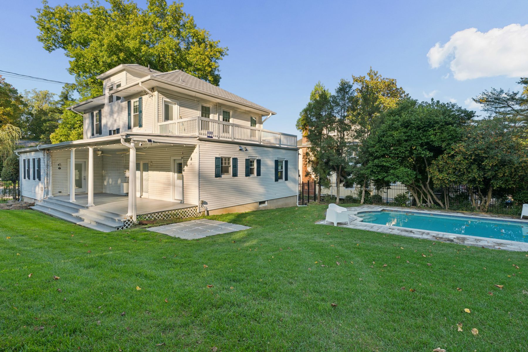 Covered rear porch with ceiling fans beside a wide lawn and the pool